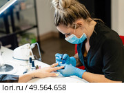 Close-up of Beautician painting her client’s nails in blue and yellow nail varnish in a beauty centre. Close-up of Beautician painting her client’s nails in blue and yellow nail varnish. Стоковое фото, агентство Ingram Publishing / Фотобанк Лори