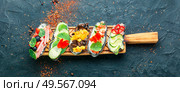 Summer bruschettas or canape with cream cheese,bacon and vegetables.Traditional italian bruschetta. Set of bruschetta on cutting board. Стоковое фото, агентство Ingram Publishing / Фотобанк Лори
