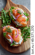 Delicious Open-Faced Sandwiches With Smoked Salmon, Cream Cheese, and Fresh Herbs on a Rustic Plate. Стоковое AI-изображение, AI-художник Юлия Гапеенко / Фотобанк Лори