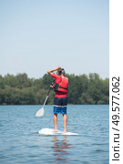 man enjoying a ride on the lake with paddleboard. Стоковое фото, агентство Ingram Publishing / Фотобанк Лори