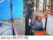 Forklift driver stacking pallet high in racking. Стоковое фото, агентство Ingram Publishing / Фотобанк Лори