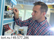 man installing a fiber optic cable in a factory. Стоковое фото, агентство Ingram Publishing / Фотобанк Лори
