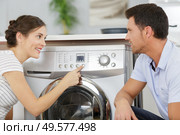 husband helping positive housewife to use washing machine indoors. Стоковое фото, агентство Ingram Publishing / Фотобанк Лори