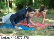 young happy athletic couple doing push-ups in park. Стоковое фото, агентство Ingram Publishing / Фотобанк Лори