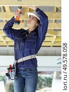 young woman pulling to the ceiling in repair loft apartment. Стоковое фото, агентство Ingram Publishing / Фотобанк Лори