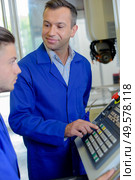 Man showing controls to younger man. Стоковое фото, агентство Ingram Publishing / Фотобанк Лори
