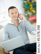 smiling man using laptop and phoning on sofa at home. Стоковое фото, агентство Ingram Publishing / Фотобанк Лори