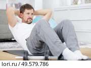 man doing ab training and crunches in living room gym. Стоковое фото, агентство Ingram Publishing / Фотобанк Лори