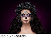 Portrait of a woman with sugar skull makeup over red background. Halloween costume and make-up. Portrait of Calavera Catrina. Стоковое фото, агентство Ingram Publishing / Фотобанк Лори