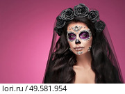 Portrait of a woman with sugar skull makeup over red background. Halloween costume and make-up. Portrait of Calavera Catrina. Стоковое фото, агентство Ingram Publishing / Фотобанк Лори