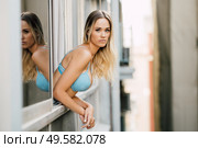 Young blonde woman in lingerie leaning out the window of her room.. Young woman in lingerie leaning out the window of her room. Стоковое фото, агентство Ingram Publishing / Фотобанк Лори
