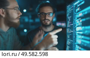 Two software developers collaborating on coding in a dimly lit tech office at night. Стоковое AI-видео, аниматор Сергей Толмачёв / Фотобанк Лори