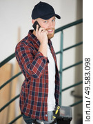 tradesman entering premises talking on his smartphone. Стоковое фото, агентство Ingram Publishing / Фотобанк Лори