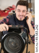 male worker on the phone while fixing a heater. Стоковое фото, агентство Ingram Publishing / Фотобанк Лори