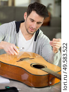 artisan lutemaker tuning handmade classic guitar with diapason. Стоковое фото, агентство Ingram Publishing / Фотобанк Лори