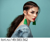 Brunette girl with perfect makeup. Beautiful model woman with curly hairstyle. Care and beauty hair products. Lady with braided hair. Model with jewelry. Turquoise background. Стоковое фото, агентство Ingram Publishing / Фотобанк Лори