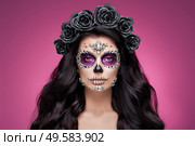Portrait of a woman with sugar skull makeup over red background. Halloween costume and make-up. Portrait of Calavera Catrina. Стоковое фото, агентство Ingram Publishing / Фотобанк Лори