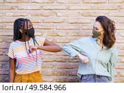 Multiethnic young women wearing masks greeting at each other with their elbows outdoors. Multiethnic young women wearing masks greeting at each other with their elbows. Стоковое фото, агентство Ingram Publishing / Фотобанк Лори