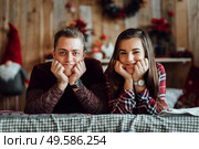 a guy and a girl celebrate the new year togetherin a warm atmosphere and give each other gifts. Стоковое фото, агентство Ingram Publishing / Фотобанк Лори
