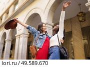 Two friends happy to see each other on the street hugging. Multiethnic women.. Two friends happy to see each other on the street hugging. Стоковое фото, агентство Ingram Publishing / Фотобанк Лори