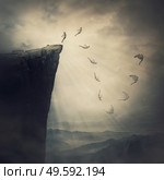 Surreal scene, determined man jumping from the edge of a cliff, fighting his fears, being confident the wings will unfold in flight. Free fall before flying. Self confidence concept, way to success. Стоковое фото, агентство Ingram Publishing / Фотобанк Лори