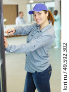 happy female worker screwing a wall in a clinic. Стоковое фото, агентство Ingram Publishing / Фотобанк Лори