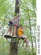 smiling people climbing on high wire in adventure park. Стоковое фото, агентство Ingram Publishing / Фотобанк Лори