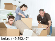 family preparing cardboard boxes idle boy on laptop. Стоковое фото, агентство Ingram Publishing / Фотобанк Лори