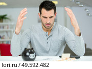 man confuse with his piggy bank calculations. Стоковое фото, агентство Ingram Publishing / Фотобанк Лори