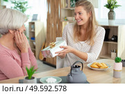 young woman congratulating her senior mother with gift box. Стоковое фото, агентство Ingram Publishing / Фотобанк Лори
