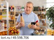 Senior man hold bottle and choose consider wine in store. Стоковое фото, фотограф Яков Филимонов / Фотобанк Лори