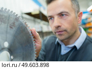 worker inspecting the blade of the circular saw. Стоковое фото, агентство Ingram Publishing / Фотобанк Лори