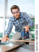handsome carpenter cutting wood at site. Стоковое фото, агентство Ingram Publishing / Фотобанк Лори
