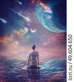 Wandering in the ocean of space. Wonderful cosmic background, surreal scene, starry night sky on another planet and a person walks in the water watching the crescent moon, meteor shower and nebulas. Стоковое фото, агентство Ingram Publishing / Фотобанк Лори