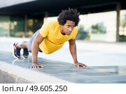 Black man doing push-ups exercising his chest on the grass of an urban park. Fitness, sport, exercising, training and people concept. Black man doing triceps dip exercise on city street bench. Стоковое фото, агентство Ingram Publishing / Фотобанк Лори
