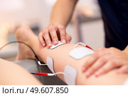 Physiotherapist applying electro stimulation in physical therapy to a young woman.. Electro stimulation in physical therapy to a young woman. Стоковое фото, агентство Ingram Publishing / Фотобанк Лори