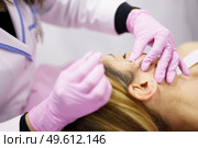 Doctor injecting PDO suture treatment threads into the face of a middle-aged woman.. Doctor injecting PDO suture treatment threads into the face of a woman. Стоковое фото, агентство Ingram Publishing / Фотобанк Лори