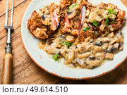 Turkey meat in cheese breading with mushroom sauce on rustic wooden table. Turkey schnitzel with fried mushrooms. Стоковое фото, агентство Ingram Publishing / Фотобанк Лори