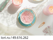 Pink flower tea in vintage porcelain tea cup, candles, flowers and notebook on white table with natural light. Romantic morning routine with healthy warm drink. Top view. Стоковое фото, агентство Ingram Publishing / Фотобанк Лори