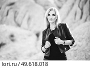 blonde girl in a black trouser suit with blue eyes on the background of a granite quarry from gray rubble. Стоковое фото, агентство Ingram Publishing / Фотобанк Лори