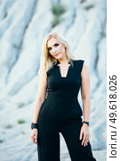 blonde girl in a black trouser suit with blue eyes on the background of a granite quarry from gray rubble. Стоковое фото, агентство Ingram Publishing / Фотобанк Лори