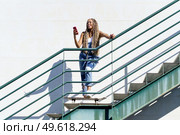 Young black woman with coloured braids, looking at her smartphone with her feet resting on a skateboard.. Black woman with coloured braids, looking at her smartphone with her feet resting on a skateboard. Стоковое фото, агентство Ingram Publishing / Фотобанк Лори