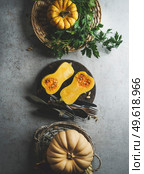 Halve of butternut squash on pale grey kitchen table with millet in bowl and kitchen utensils. Preparing healthy vegan millet porridge at home with seasonal autumn ingredients. Top view. Стоковое фото, агентство Ingram Publishing / Фотобанк Лори
