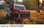 A red accordion is sitting on the grass next to a tree. Стоковое AI-видео, аниматор Виктория Кольцова / Фотобанк Лори