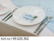 The presidium of the newlyweds in the banquet hall of the restaurant is decorated with candles and green plants, wisteria hangs from the ceiling. Стоковое фото, агентство Ingram Publishing / Фотобанк Лори