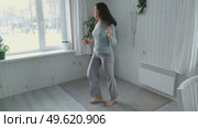 Brunette woman dance, have fun at home listens song, moves to music, feels overjoyed, celebrate good news, relish carefree life looks happy. Young adult female twirls, grooves. Lady dancing in kitchen. Стоковое видео, видеограф Марина Демидюк / Фотобанк Лори