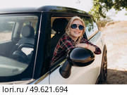 blonde with pigtails in a shirt, jeans, red shoes and black glasses near a white car. Стоковое фото, агентство Ingram Publishing / Фотобанк Лори