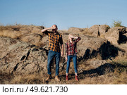 Guy and girl in caged shirts and trekking shoes on granite rocks. Стоковое фото, агентство Ingram Publishing / Фотобанк Лори