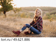 blonde with pigtails in a shirt, jeans, red shoes smiling at sunset. Стоковое фото, агентство Ingram Publishing / Фотобанк Лори