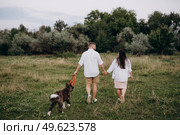 Big dog for a walk with a guy and a girl on the green prairie. Стоковое фото, агентство Ingram Publishing / Фотобанк Лори
